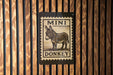 a sign with a donkey illustration on it, mounted on a wooden wall.
