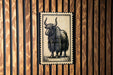 a wooden wall with a framed illustration of a yak, which is a large, horned mammal native to the Himalayan region.
