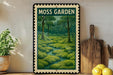 A framed illustration of a lush, green moss garden is displayed on a shelf, accompanied by a wooden cutting board and a potted plant.