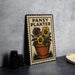 A metal sign with a floral design and text, placed on a table next to some black camera lenses.