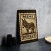 a sign with a donkey illustration, placed on a countertop next to some black camera lenses.