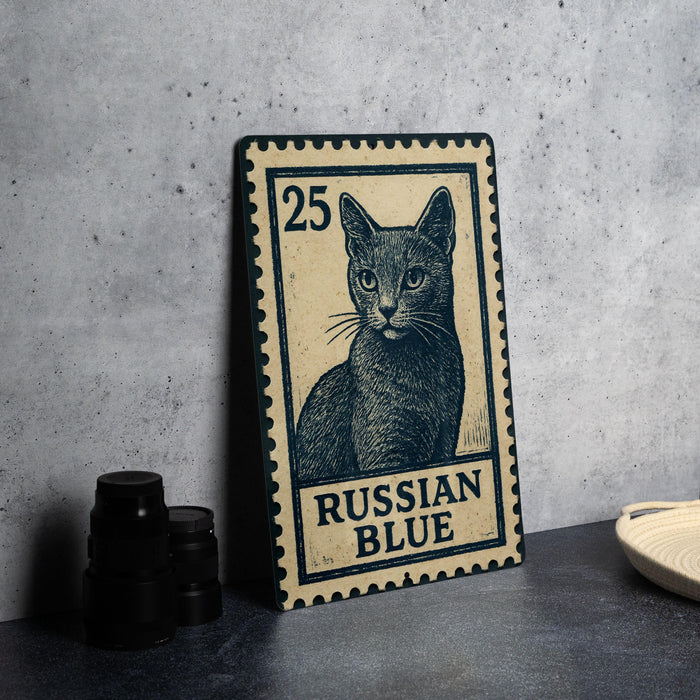 A wooden postcard featuring a cat illustration, with the text "Russian Blue" printed on it, is displayed on a table next to some black camera lenses.