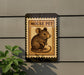 a sign with a mouse illustration, mounted on a wall next to a plant.