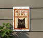 a sign with a cat wearing glasses and the text "MY CAT IS MY THERAPIST" on it, mounted on a wall next to a plant.