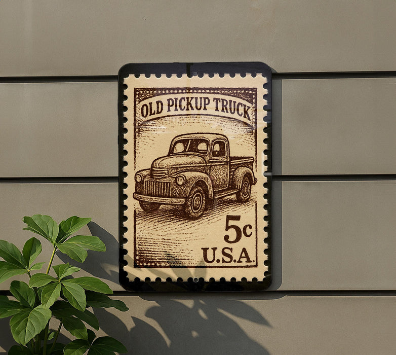 a stamp-like sign with an illustration of an old pickup truck, mounted on a wall.