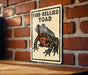 a sign with a picture of a fire-bellied toad on it, mounted on a brick wall.