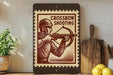 a wooden frame with a vintage-style stamp depicting a man holding a crossbow, placed on a wooden surface next to a wooden cutting board and some lemons.