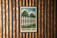 A white picket fence is depicted on a wooden wall, with a USA 24 postage stamp in the center.