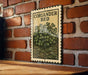 A vintage-style metal sign with the text "CORIANDER BED" is displayed on a brick wall, with a wooden table below it.