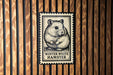 A metal stamp featuring a hamster on a wooden background.