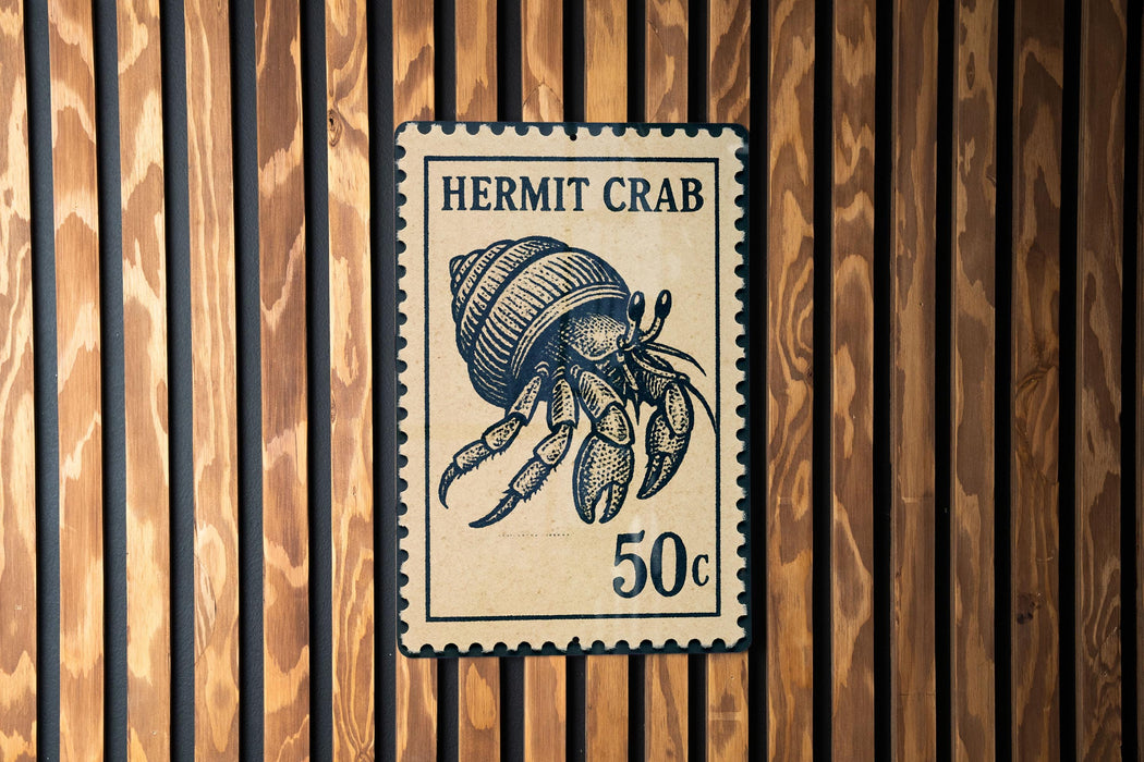 A Hermit Crab postage stamp is displayed on a wooden wall.