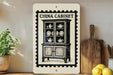 a China Cabinet sign on a shelf, surrounded by kitchen utensils and a potted plant.