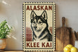 A vintage-style sign featuring a black and white illustration of a husky dog, with the text "ALASKAN KLEE KAI" prominently displayed.
