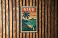 A vintage-style postage stamp featuring a tropical landscape with palm trees and a sunset over a body of water.