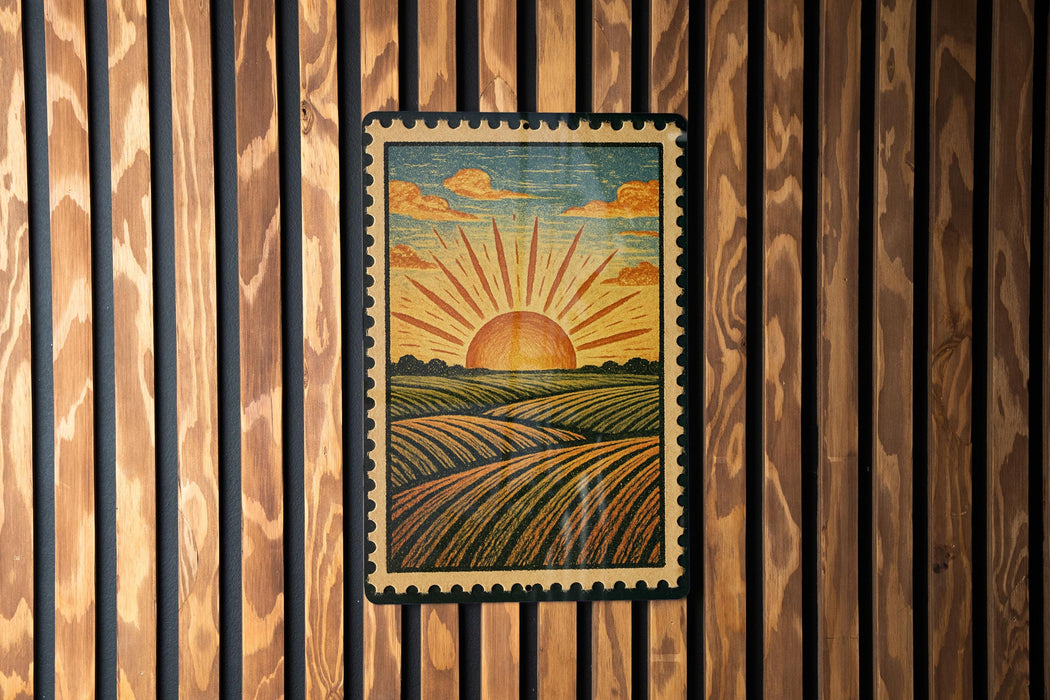 A framed illustration of a sunrise over a field is displayed on a wooden wall.