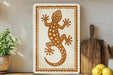 a decorative sign with a lizard design, placed on a shelf next to a wooden cutting board and some lemons.