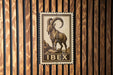 a metal stamp with a depiction of a ram, mounted on a wooden wall.