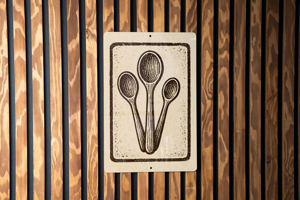 a sign with a stylized illustration of three spoons, mounted on a wooden wall.