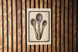 a sign with a stylized illustration of three spoons, mounted on a wooden wall.