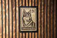 A postage stamp featuring a close-up of a Tamaskan dog, which is a type of wolf dog.