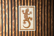 a wooden wall with a rectangular sign featuring a stylized illustration of a lizard.