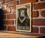 A wooden surface with a framed image of a black bear on it, mounted on a brick wall.