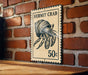 A vintage-style stamp featuring a hermit crab, mounted on a brick wall.