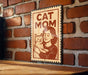A sign with the text "CAT MOM" and an illustration of a woman holding a cat.