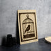a wooden sign with a bird inside a cage, placed on a table next to some black camera lenses.