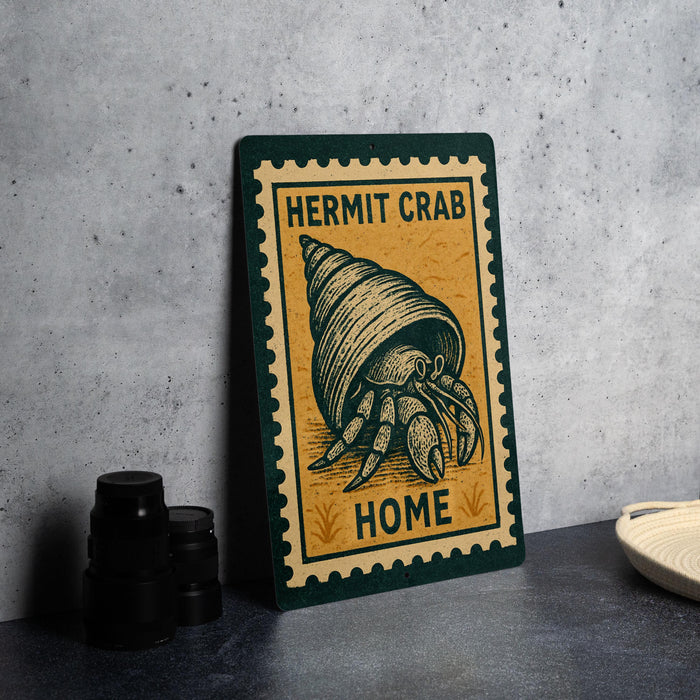 a sign with a crab illustration and the text "HERMIT CRAB HOME" on it, placed on a countertop next to some black camera lenses.