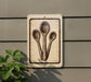 a sign with a drawing of three spoons on it, mounted on a wall next to a plant.
