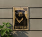 a wooden sign with a black and white illustration of a bear, mounted on a wall.