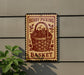 A sign for a berry picking basket hangs on a wall, featuring a basket filled with berries and leaves.