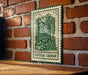 A green and white sign with a decorative illustration of a vertical garden is mounted on a brick wall.