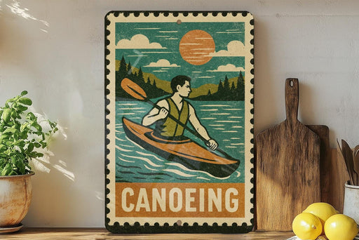 A vintage-style metal sign with a canoe illustration and the word "Canoeing" printed on it, displayed on a shelf next to a potted plant and kitchen utensils.