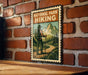 A vintage-style metal sign with a hiker illustration, mounted on a brick wall.