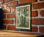 A framed image of bamboo plants is hanging on a brick wall.