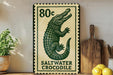 A framed poster of a saltwater crocodile is displayed on a wall, with a wooden cutting board and a potted plant to the side.