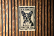 a sign with a dog's face on it, mounted on a wooden wall.