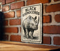 a sign with a rhinoceros illustration on it, mounted on a brick wall.