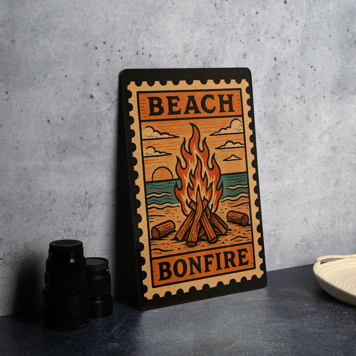 A metal sign with a beach scene and a bonfire, featuring the text "BEACH BONFIRE" on it.