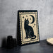 A framed illustration of a cat sitting on a crescent moon and starry night sky, with a black and white color scheme.
