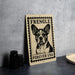 a metal sign with a dog illustration and the text "FREINGLE FOREVER USA" on it, placed on a countertop next to some black camera lenses.