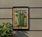 a framed print of bamboo plants hanging on a wall, with a plant to the left of the frame.