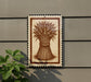a decorative sign with a wheat stalk design, mounted on a wall next to a plant.