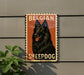 A vintage-style sign featuring a black dog with a red tongue, mounted on a gray wall next to a plant.