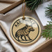 A circular ornament with a black and white illustration of a hyena, and the word "Aardwolf" written around the edge.