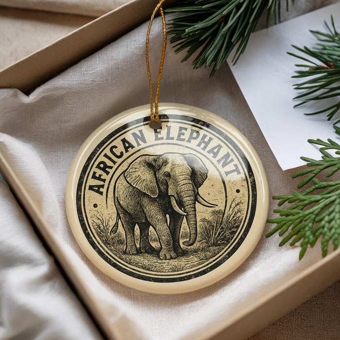 A decorative ornament featuring an elephant is displayed in a box, surrounded by pine branches.