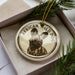 A circular ornament featuring a wild dog image, placed in a box with pine branches.