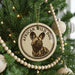 A circular ornament on a Christmas tree featuring an image of a wild dog.
